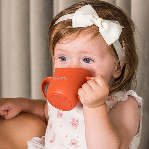 Babyono mācību krūzīte bērniem, attēlā redzams bērns, kas dzer no krūzītes.