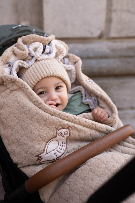 Lodger Bunker Folklore Fleece vissezonas guļammaiss beige krāsa, bildē mazulis guļammaisā un ratiņos.