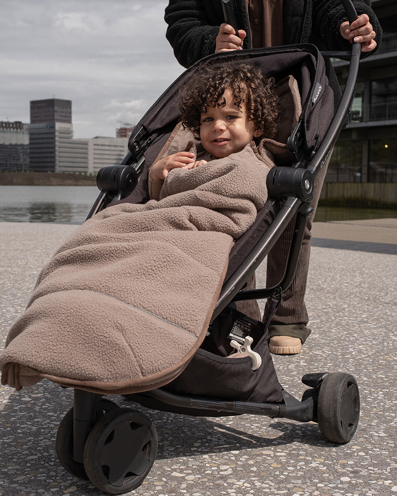 Lodger Mini Bunker Teddy vissezonas guļammaiss buffalo krāsa, bildē mazulis ratiņos ar guļammaisu.