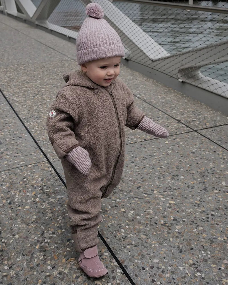 Lodger Mittens Folklore Merino vilnas bērnu cimdiņi rose krāsa, bildē mazulis ar cepurīti un cimdiņiem.