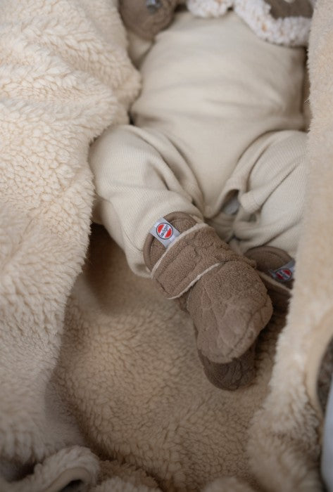 Lodger slipper fleece čībiņas buffalo krāsā redzama uzvilkta uz mazuliša kājiņas