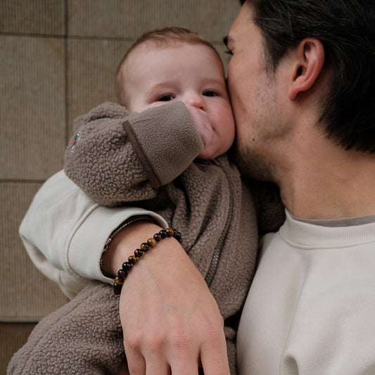 Lodger Skier Teddy kombinezons, Buffalo, SKT 535, bildē mazules vecāka rokās ar kombinezonu.