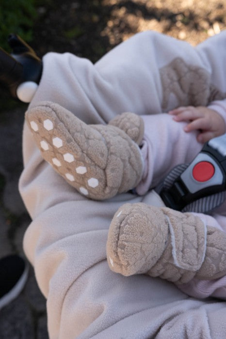 Lodger slipper flīsa čībiņas beige krāsā redzamas uzvilktas uz mazuļa kājiņām