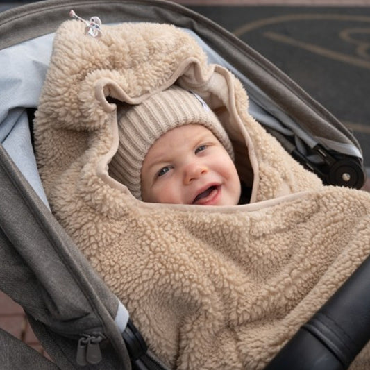 Lodger Wrapper Teddy sedziņa beige krāsā. Redzams bērns ietīts sedziņā.