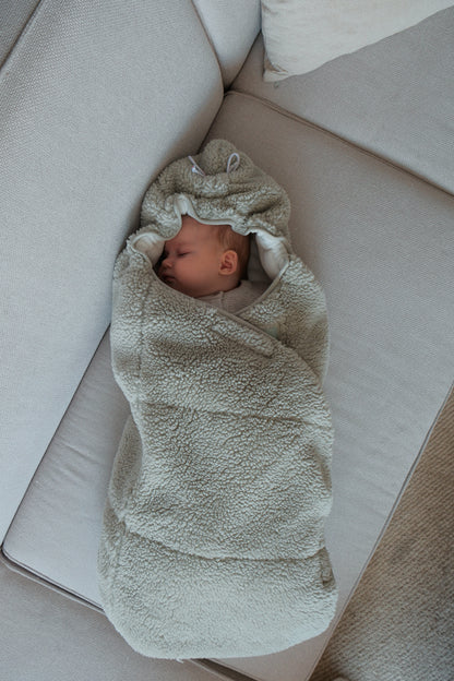 Lodger Wrapper Teddy ietinamā sedziņa silk krāsā. Redzams guļošs mazulītis ietīts sedziņā