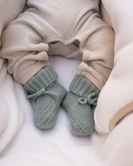 Lodger Slipper Merino vilnas čībiņas silk krāsā. Redzamas no priekšpuses un sāna, uzvilktas uz mazuļa kājiņām.