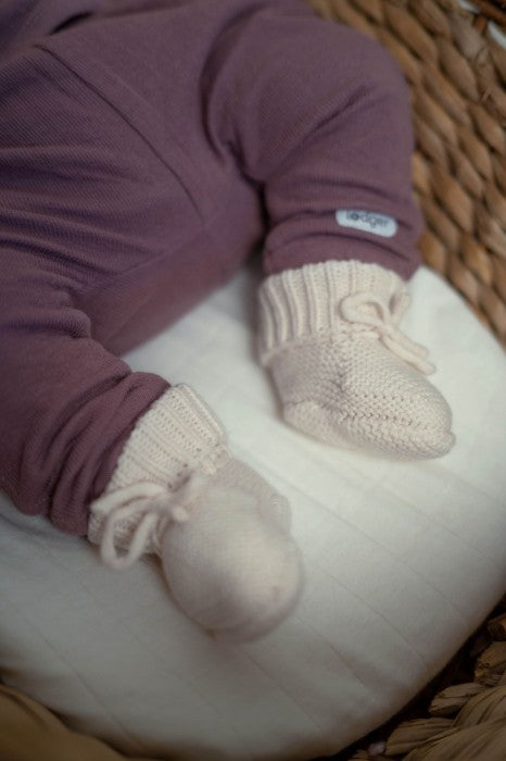 Lodger Slipper Merino vilnas čībiņas birch krāsā. Redzamas no sāna un priekšpuses, uzvilktas uz mazuļa kājiņām.