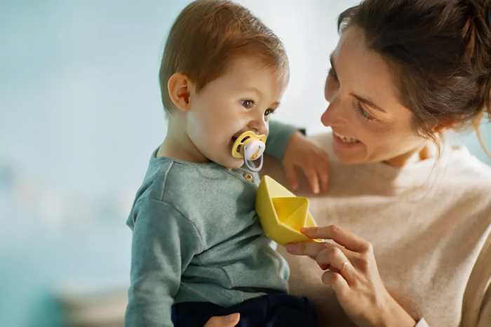 Philips Avent Māneklītis Ultra Air Deco, redzams dzeltens māneklītis ar ābola zīmējumu, kas ir bērnam mutē.